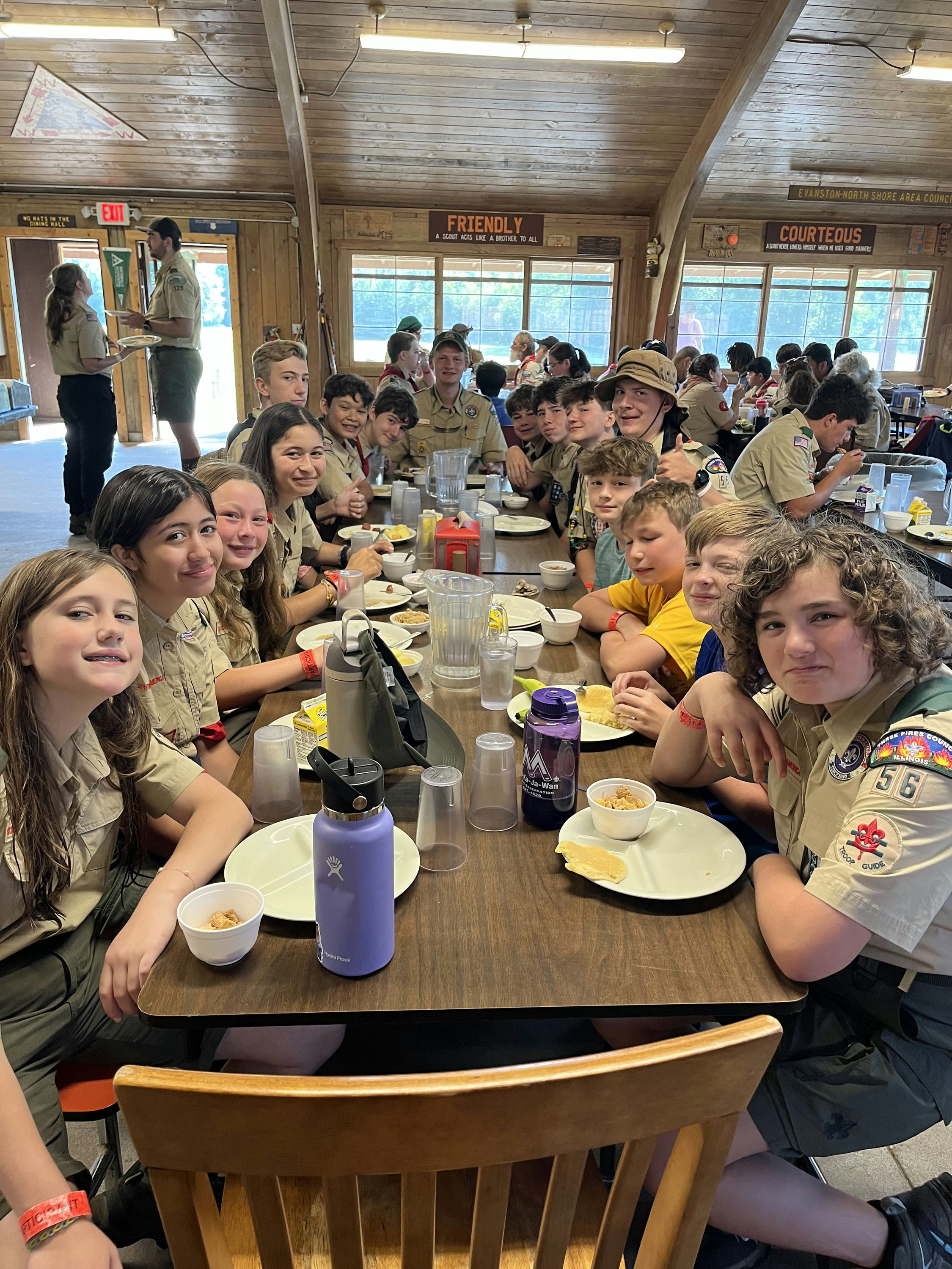 Scouts sit around a table in the dining hall, enjoying a meal